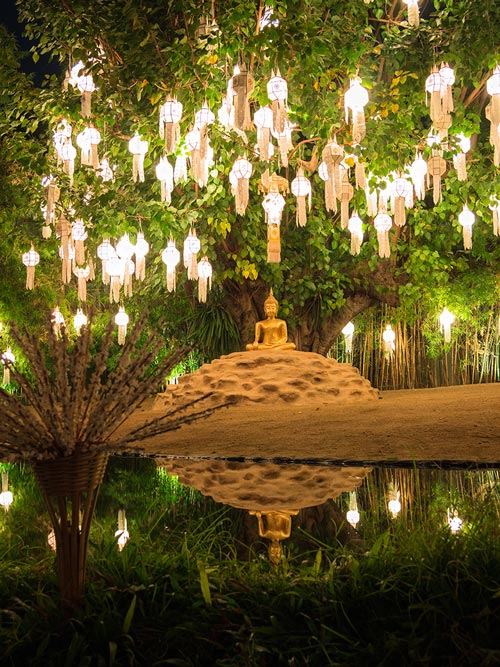 golden buddha in meditation surrounded by lights in trees